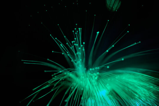 Glowing fiber optic strands on dark abstract background