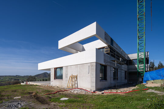 Modern house construction with crane and unfinished concrete facade