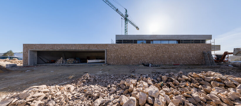 Modern house construction with crane and stone foundation