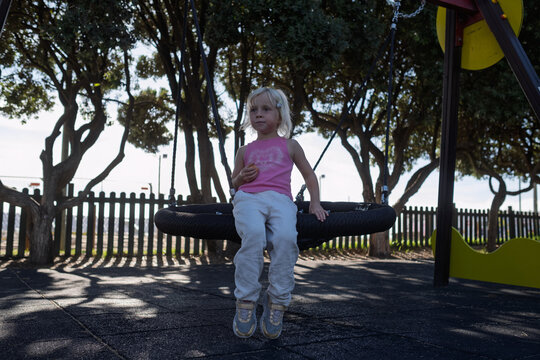 Little Blonde Girl Sitting on Web Nest Swing at Outdoor Playground