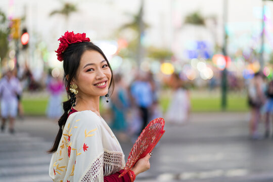 Smiling woman in flamenco dress with fan in Malaga