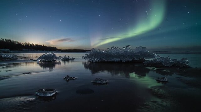 Mirroring ice cluster reflecting green aurora over tidal flat, with aurora intensifying seaward
