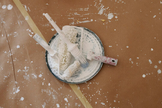 Painting tools and paint bucket lid on protected floor