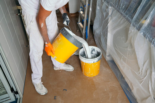 Professional painter pour white paint during home renovation