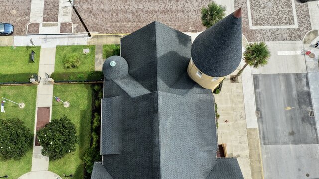Aerial view of Ancient City Baptist Church with its distinctive conical tower and dark shingled roof surrounded by green lawns and paved streets in St. Augustine, Florida, United States.