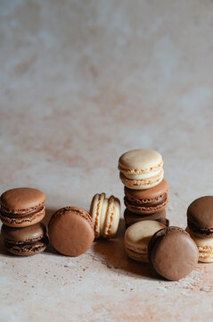 Assorted chocolate macarons stacked on rustic table