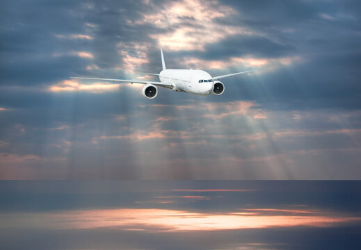 Airplane flying over tropical sea at sunset