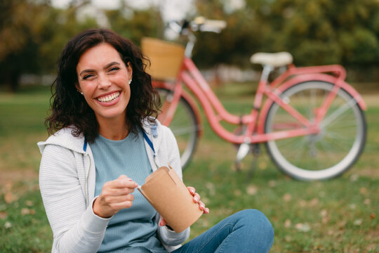 Smiling woman enjoying healthy outdoor picnic with bicycle