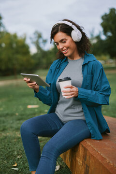 Woman working remotely outdoors using digital tablet with headphones