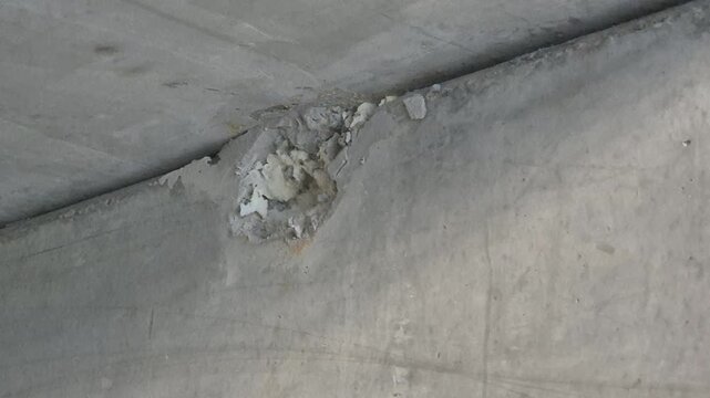 Slow motion close-up of the first hammer strikes on the upper part of a concrete wall during the initial steps of the demolition.