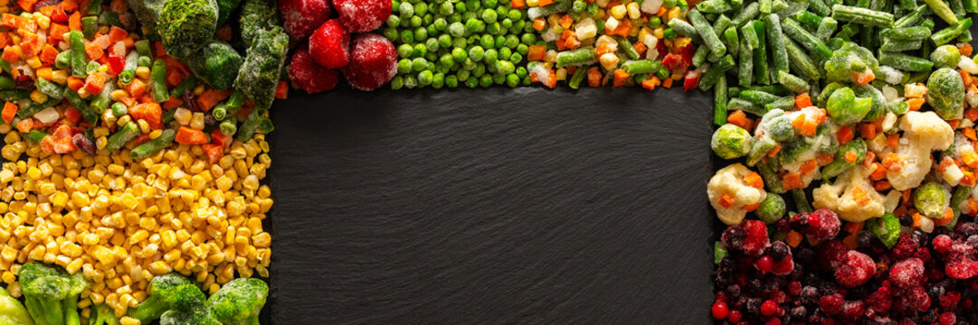 Organic, fresh fruits and vegetables frozen and prepared on a dark ebonite board, perfect for preserving the summer harvest and ensuring healthy, nutritious meals for the winter, banner