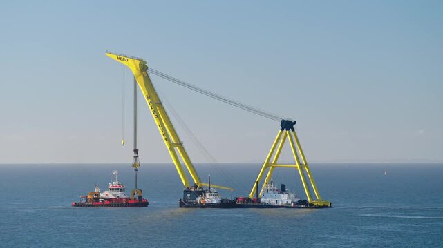 Time lapse of HEBO Lift 9 floating sheerleg crane working at the Fehmarnbelt tunnel construction site near R&oslash;dbyhavn, while workboats and service vessels move through the working area.
