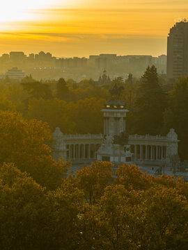 Aerial view of the Monument to Alfonso XII in El Retiro Park surrounded by autumn trees during golden hour in Madrid, Community of Madrid, Spain.