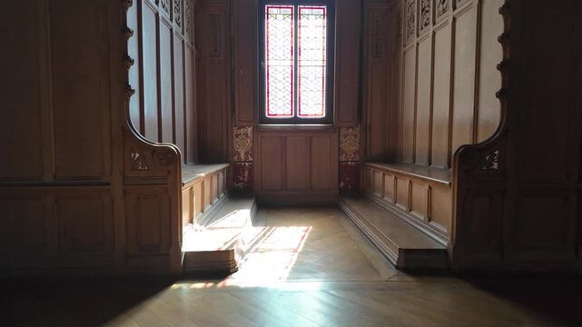 Slow motion forward push through a historic wooden chamber at Ch&acirc;teau de Pierrefonds, showing carved paneling, built-in benches and stained glass