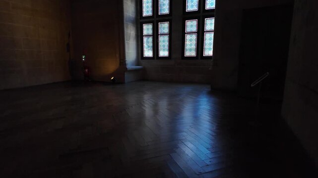 Stone hall at Ch&acirc;teau de Pierrefonds featuring patterned stained glass windows, polished flooring, masonry walls and subdued interior lighting