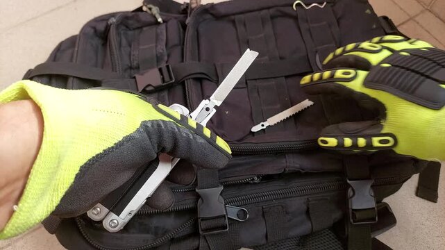 Gloved hands swapping file for saw blade on heavy duty multitool, close up top view