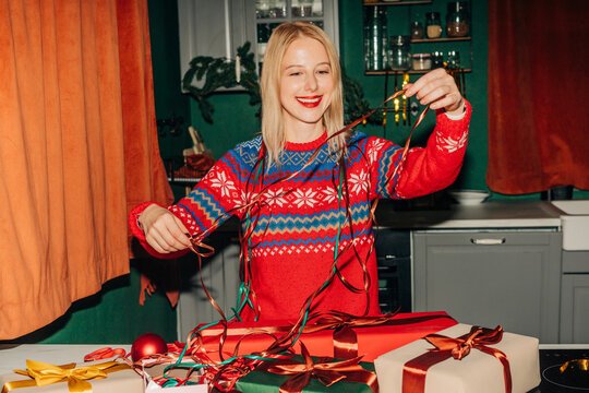 Woman wrapping Christmas gifts at kitchen table