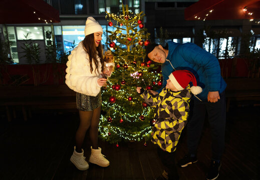 Happy family celebrate Christmas by tree in city evening