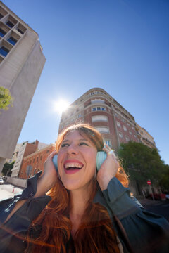 Happy woman listen to music with headphones on street