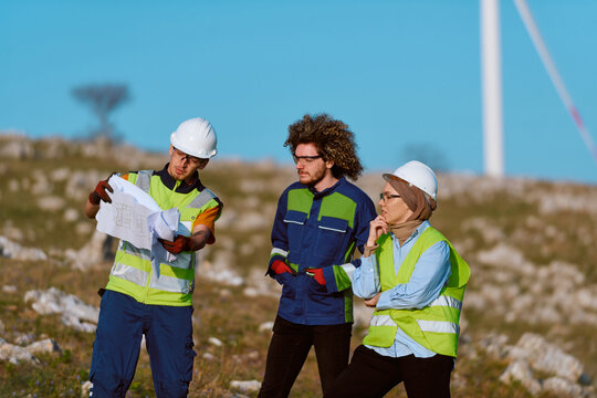Engineers Discuss Wind Farm Plans on Site Wearing Safety Gear and Reflective Vests During Renewable Energy Project