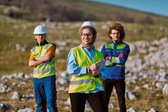 Diverse Field Engineers in Hard Hats and Hi‑Vis Vests Leading Outdoor Construction Site Inspection