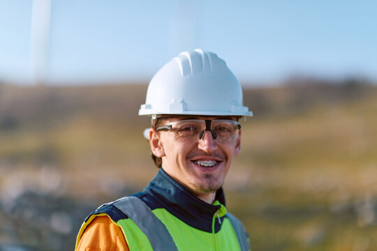 Portrait Of A Smiling Construction Worker Wearing Hardhat And High-Visibility Vest At Outdoor Job Site