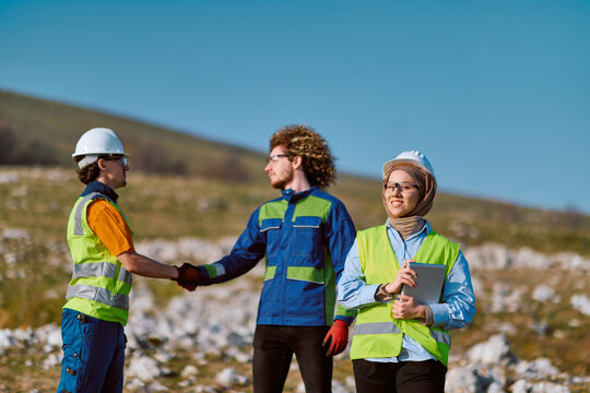 Construction Engineers and Multicultural Team Shaking Hands on Outdoor Job Site While Female Engineer Holds Tablet