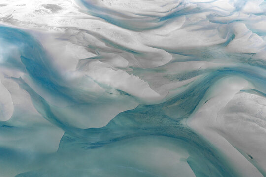 Aerial view of the snow-covered landscape of Senja, featuring intricate patterns of frozen water and glacial textures in shades of white and blue in Senja, Troms, Norway.