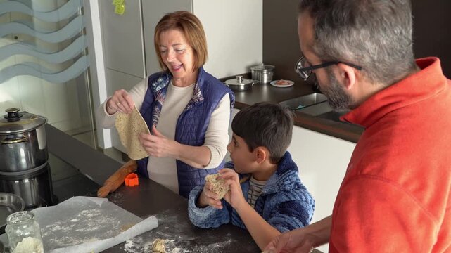 Happy senior grandmother cooking christmas cookies with her family