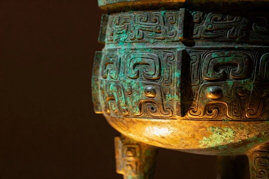 Close-up of an ancient bronze vessel with intricate geometric and mythical motifs, showing patina and aged surface details.