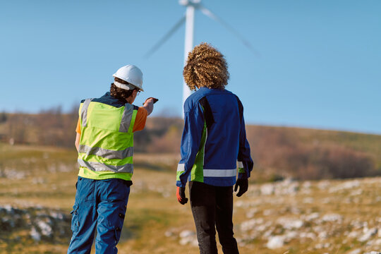 Two Field Technicians Inspect Wind Turbine and Discuss Renewable Energy Site Safety and Maintenance