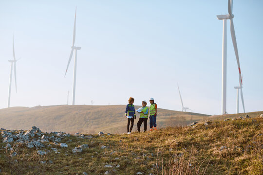 Engineers Inspecting Wind Turbines on Wind Farm Hilltop During Renewable Energy Site Survey