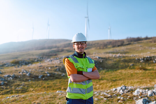 Wind Farm Technician Wearing Hard Hat And High-Visibility Vest At Renewable Energy Site Outdoors