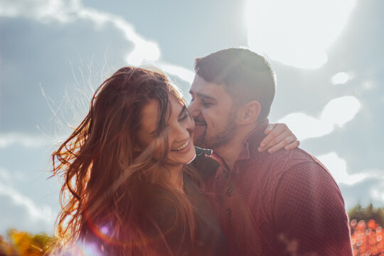 Smiling couple embracing outdoors under sunlight