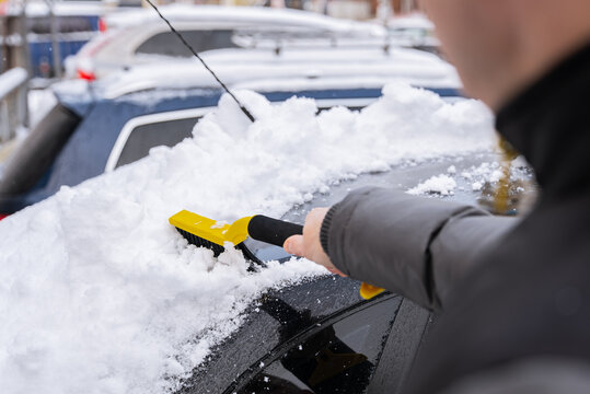 Man remove snow from car windshield in cold weather
