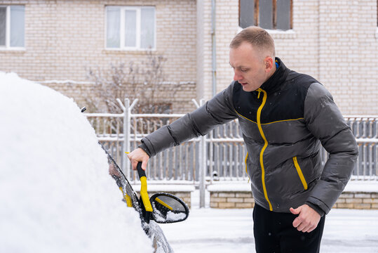 Man remove snow from car during winter weather