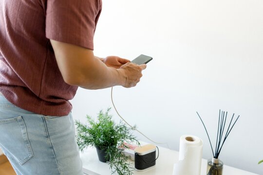 Man charge smartphone at home beside table