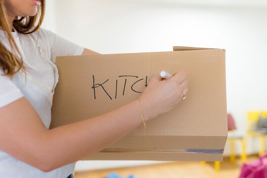 Woman labeling cardboard box during home relocation