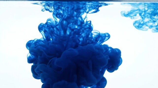 Blue ink swirling in clear water forming an abstract fluid cloud isolated on white background