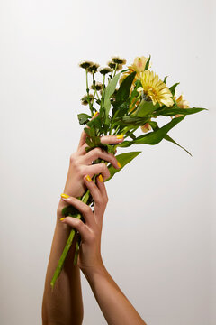 Woman hands with yellow manicure hold yellow flower bouquet
