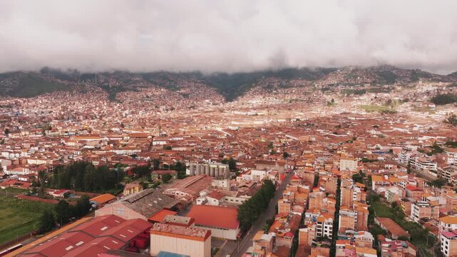 Cinematic aerial drone view over historic Cusco city and the surrounding Andes Mountains in Peru
