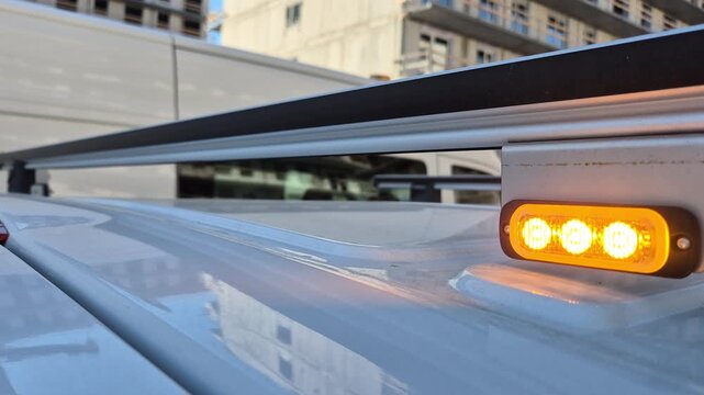 Close-up shot of a flashing amber warning light strobe beacon blinking on the back of a delivery truck or transport commercial vehicle.