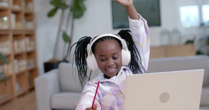 African female child watching laptop at home writing with red pencil raising hand requesting help