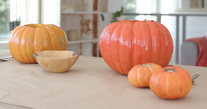 Camera is shifting focus and exposure, revealing glossy orange pumpkins on table for halloween