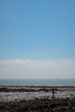 Wide View of Mudflat Shoreline and Ocean Horizon under Clear Blue Sky at Jebudo Island in South Korea, Sparkling Sea Water with Rocks and Mud in Coastal Nature Landscape View Daytime