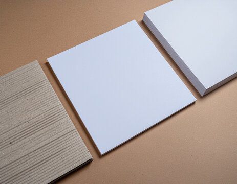 blank white paper sheets and corrugated cardboard mockup on brown background