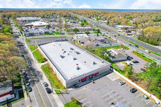 Commercial real estate aerial view. Large retail building with flat roof and parking lot. Suburban shopping center location near main road and highway intersection during spring time