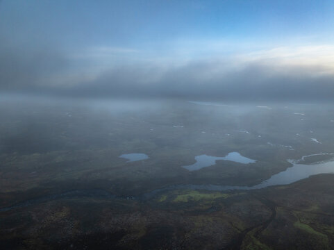 Aerial view of the scenery over a mountain range with clouds and fog - Iceland