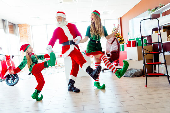 Santa dancing with two elves in a joyful family Christmas scene in a decorated living room with gifts and holiday cheer