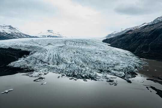 Aerial view of Vatnajokull glacier with its rugged ice formations and glacial lake surrounded by mountains in Iceland.